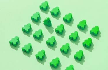 Groene houten poppetjes, allemaal liggend behalve één die rechtop staat, symbool voor regels en mens