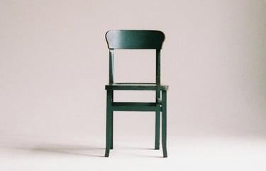 Een lege houten stoel staat uitnodigend klaar, symbool voor de ouder die nog niet in gesprek is.