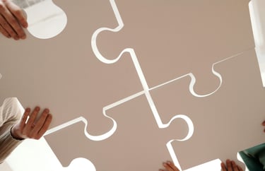 Vier mensen houden grote puzzelstukken samen vast, symbool voor samenwerking en verbinding.