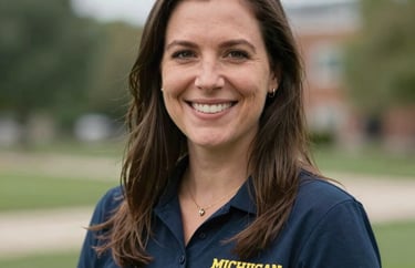 Professional headshot of a female volunteer coordinator with a warm smile, set against a blurred Michigan outdoor background. Professional and approachable.