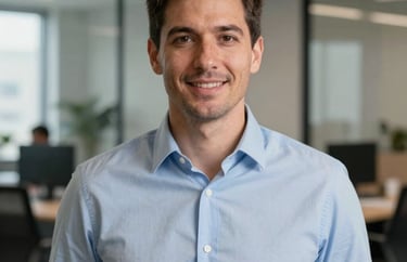 A professional headshot of a man in a business-casual light blue shirt, standing in a contemporary Indiana office suite.