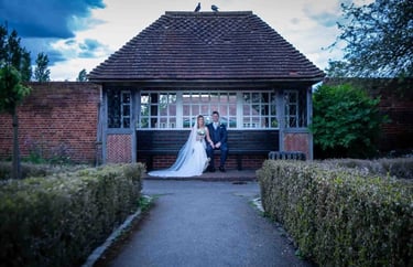 A bride and groom posing for a wedding portrait in a garden gazebo at sunset.
