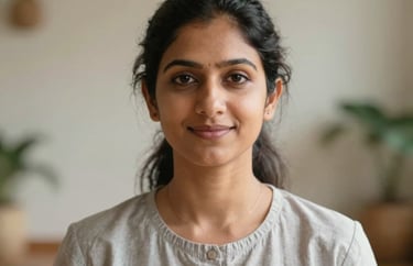 A headshot of a South Asian female yoga therapist in a serene indoor studio, wearing professional attire, peaceful and trustworthy expression.