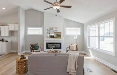 Living room with a fireplace, seating area, and ceiling fan.