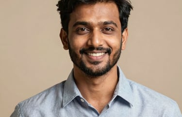 Professional studio portrait of a South Asian / Indian man with a friendly smile, wearing a modern shirt, set against a soft beige backdrop.