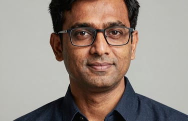 Professional studio portrait of a South Asian / Indian man with glasses, looking professional and trustworthy.
