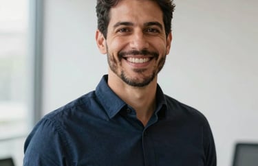 Professional portrait of a male Brazilian leadership coach with a warm smile, wearing a dark navy blue shirt, soft natural lighting in a modern professional setting, crisp white background elements.