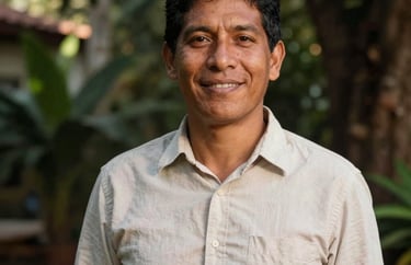 Portrait of a South American / Brazilian man in his late 20s, with a friendly face, wearing a simple cotton shirt, standing in a garden with sunlight dappling through trees.