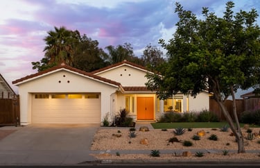 a white Spanish style house with a pink front door