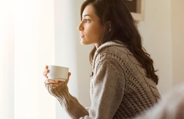 Woman holding a warm drink while taking a quiet moment to relax and reset after stress