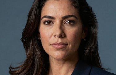 Professional headshot of a South American / Brazilian female legal expert, professional attire, soft Steel Blue background lighting.
