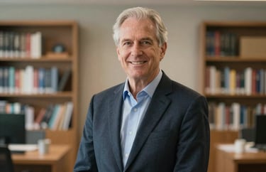 A professional portrait of a senior clinical director in professional attire, standing in a brightly lit North American / US office with a blurred background of bookshelves.