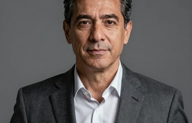 Professional headshot of a mature businessman in a dark gray suit, neutral background, looking directly at the camera with a confident expression, South American / Brazilian style.