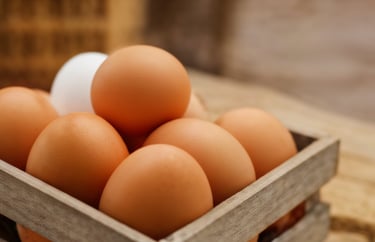 Close up photo of brown eggs in a wooden tray.