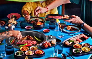 Friends dining at a Korean BBQ restaurant with wagyu beef grilling over an inset tabletop burner.