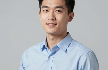 Professional studio portrait of a young Southeast Asian male consultant in a light blue shirt, looking energetic and skilled. Neutral light grey background.
