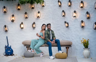 An outdoor photo shoot setting with a couple posing on a bench, with a guitar, and decorative lanter