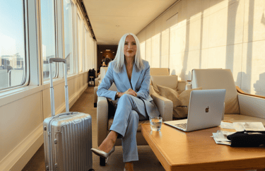Businesswoman in tailleur azzurro in aeroporto con trolley e laptop-