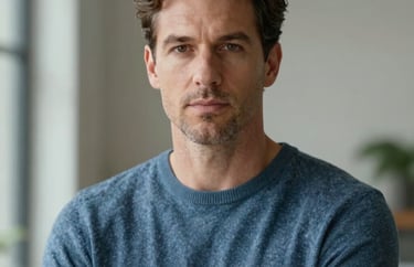 Portrait of a distinguished man in a slate blue sweater, looking forward with confidence and compassion, North American professional, soft natural lighting.