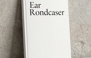 A minimalist book cover design leaning against a neutral stone wall. The design is elegant, featuring sophisticated serif typography and plenty of white space.