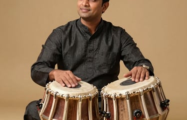 Professional portrait of a male South Asian / Indian percussionist in a charcoal black kurta, sitting gracefully with a pair of professional tablas, warm gold lighting, premium photography.