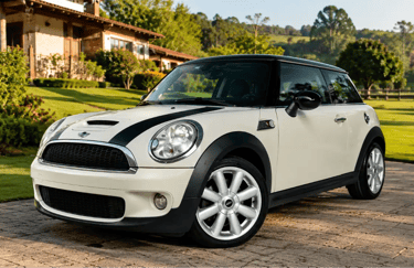 Mini Cooper branco estacionado em frente a casa de campo com jardim e gramado.