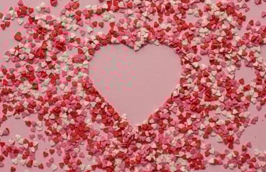Sur fond rose, coeur représenté par des pailletes coeur roses, rouges et blanches