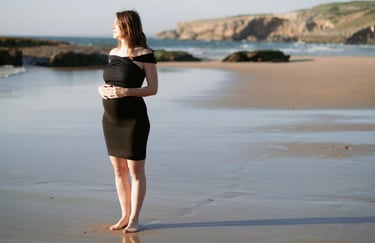 a pregnant woman standing on a beach