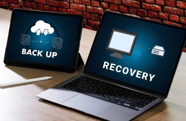 A laptop and tablet showing cloud backup and data recovery icons on their screens.