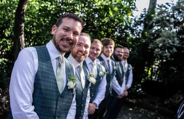 Smiling groom and groomsmen in Abbey Gardens Bury St Edmunds.