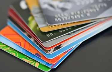 A fanned-out stack of colorful credit cards and debit cards on a dark reflective surface.