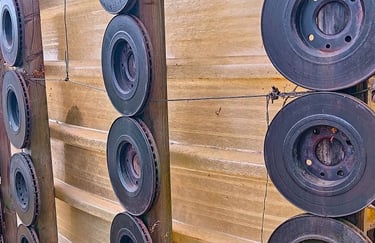 Used car brake rotors mounted on vertical wooden posts as a creative metal wall decoration.