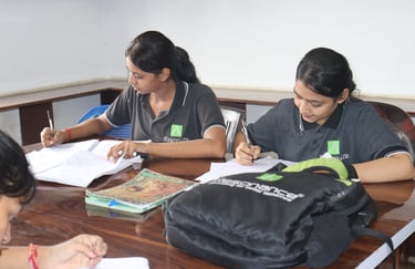 Students in Resonance uniforms studying and writing notes during a classroom session.