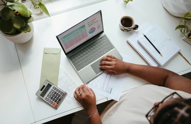 Lady sitting at a desk with a laptop and calculator working on tracking her bills.