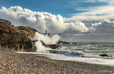 a lighthouse on a rocky beach with waves crashing over the rocks