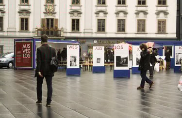 Menschen gehen durch die Ausstellung "Aus weg los!" auf der Grazer Hauptplatz.