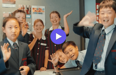 children in school uniforms waving to the camera