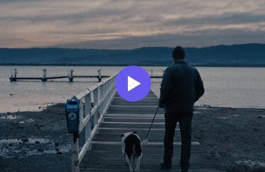 man and dog walking towards a jetty