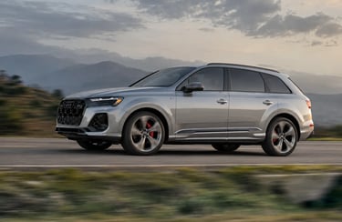 Audi Q7 2027 em movimento numa estrada com montanhas ao fundo