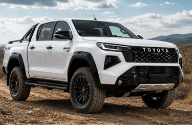 Toyota Hilux 2027 branca em estrada de terra e cascalho com vegetação rasteira