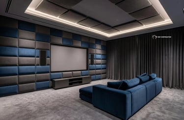 Modern home theater room featuring a blue velvet sofa, acoustic wall panels, and a large projection screen.