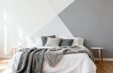 Modern minimalist bedroom with a grey geometric accent wall, cozy faux fur throw, and neutral bedding.