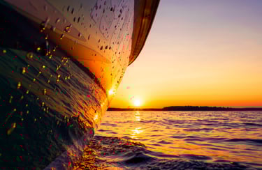 Beautiful picture of a boat hull at the waterline reflecting the gorgeous sunset.