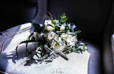 Elegant white wedding bouquet with roses and eucalyptus leaves resting on a vintage armchair.