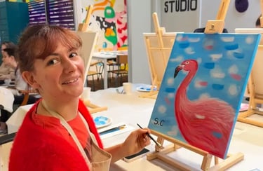 Une femme souriante peint un flamant rose sur une toile lors d’un atelier in strasbourg