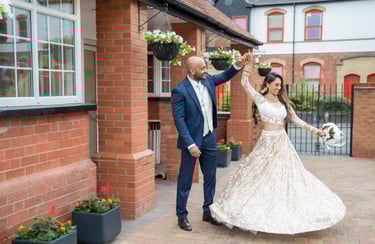 asian bride and groom dancing and both smiling, wall framing them 