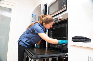 a woman in a blue shirt is cleaning a oven