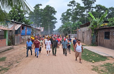 A community group guided by Roger Bardales walking down a dirt road in a indigenous shipibo village.