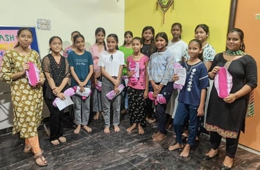 Small class of schoolgirls holding up a Hanaru reusable sanitary napkin