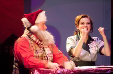 a man and woman in santa claus costume on stage at theater performance